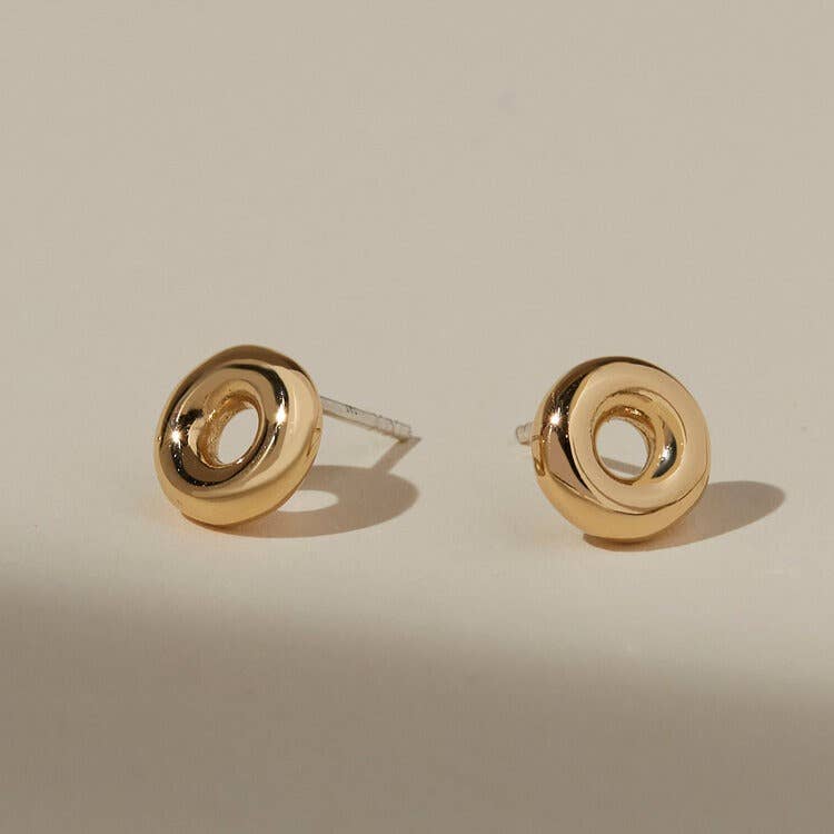 mia stud earrings on a beige background - round gold donut shaped studs with silver posts