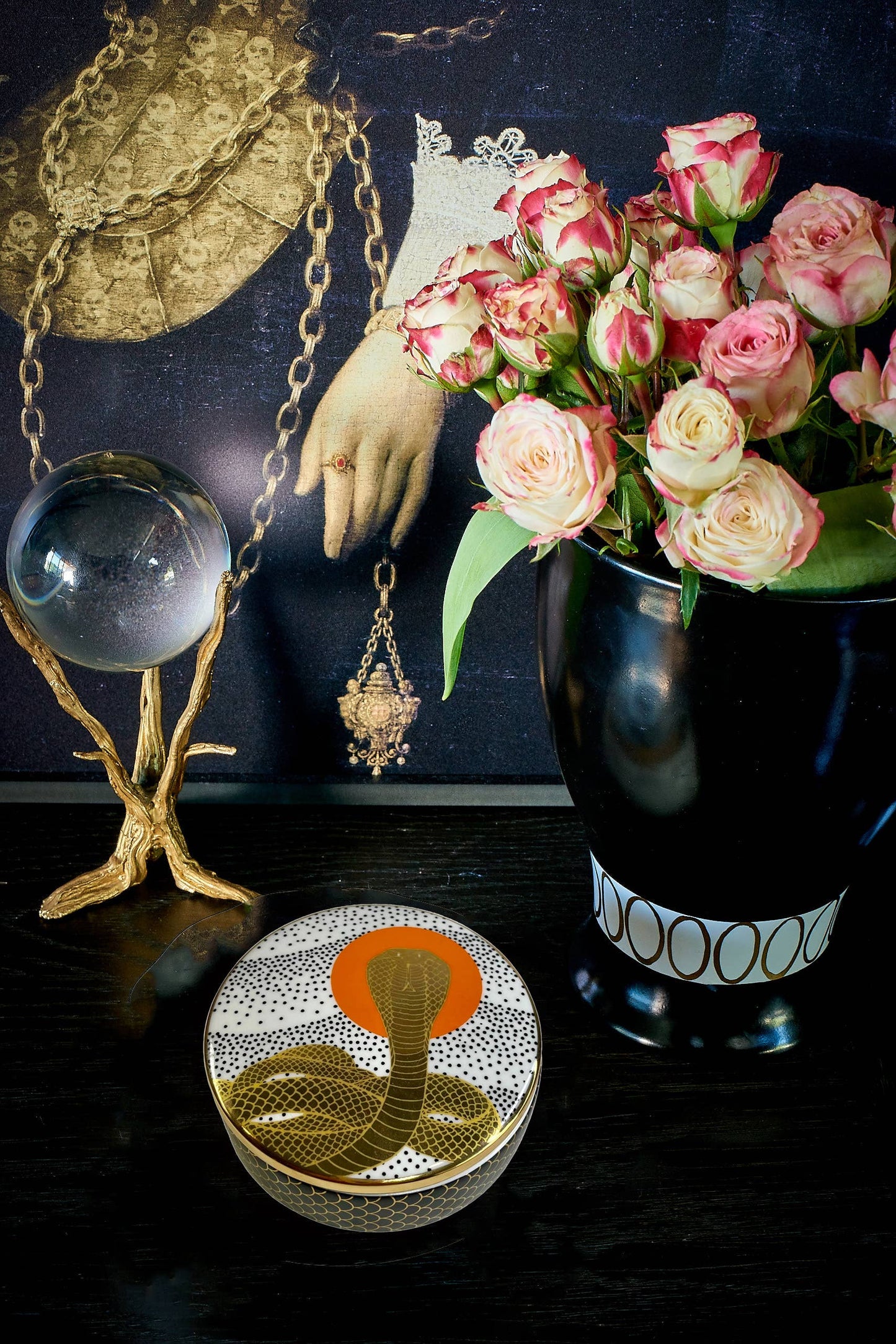 cobra rising trinket dish on a back table with a glass ball and a vase of roses