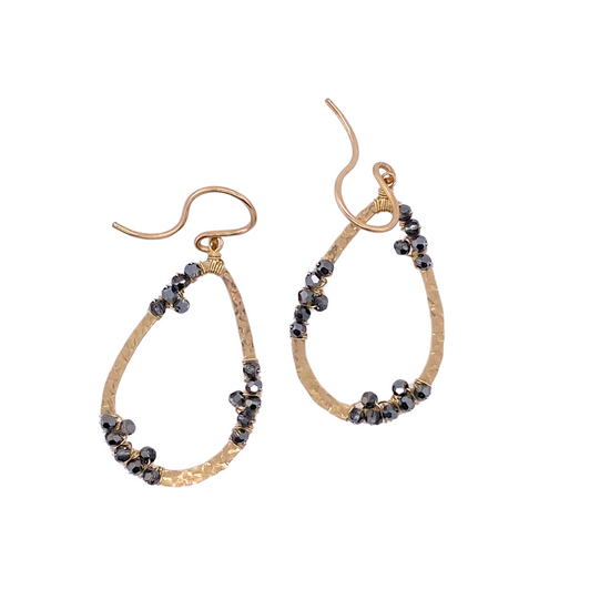 teardrop shaped gold earrings with asymmetrical black bead clusters on a white background