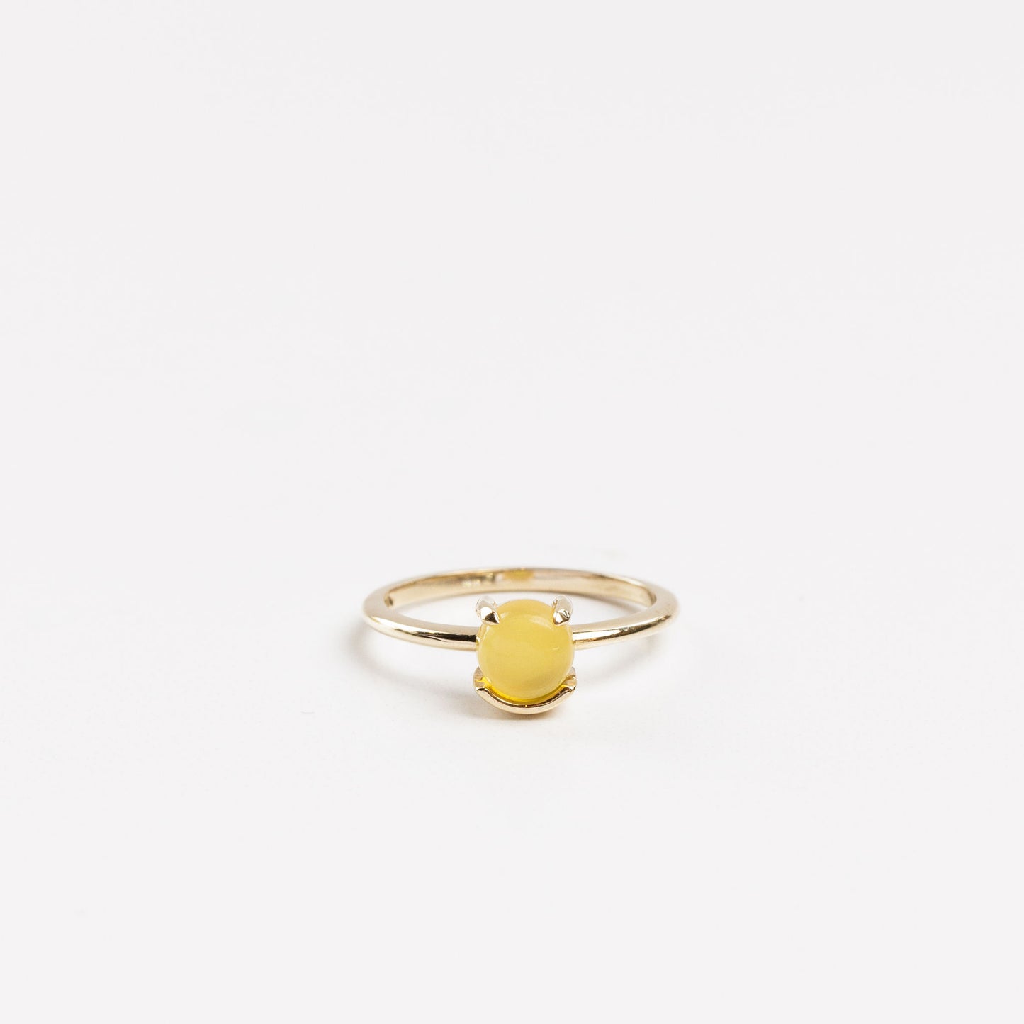 yellow gold solitaire ring with a yellow chalcedony half prong half bezel set on a white background