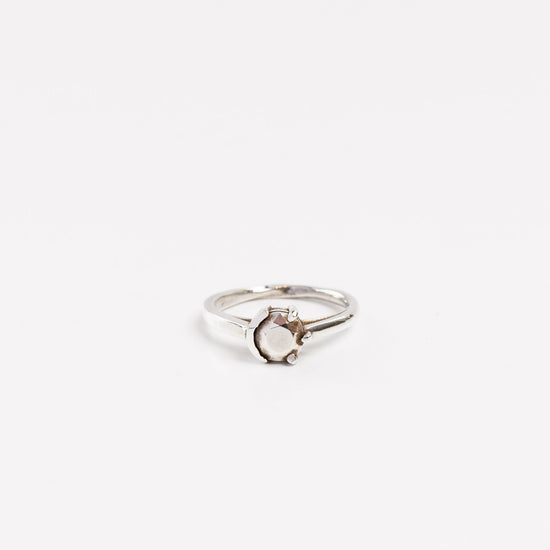 sterling silver ring with fine silver gem half bezel set half prong set on a white background