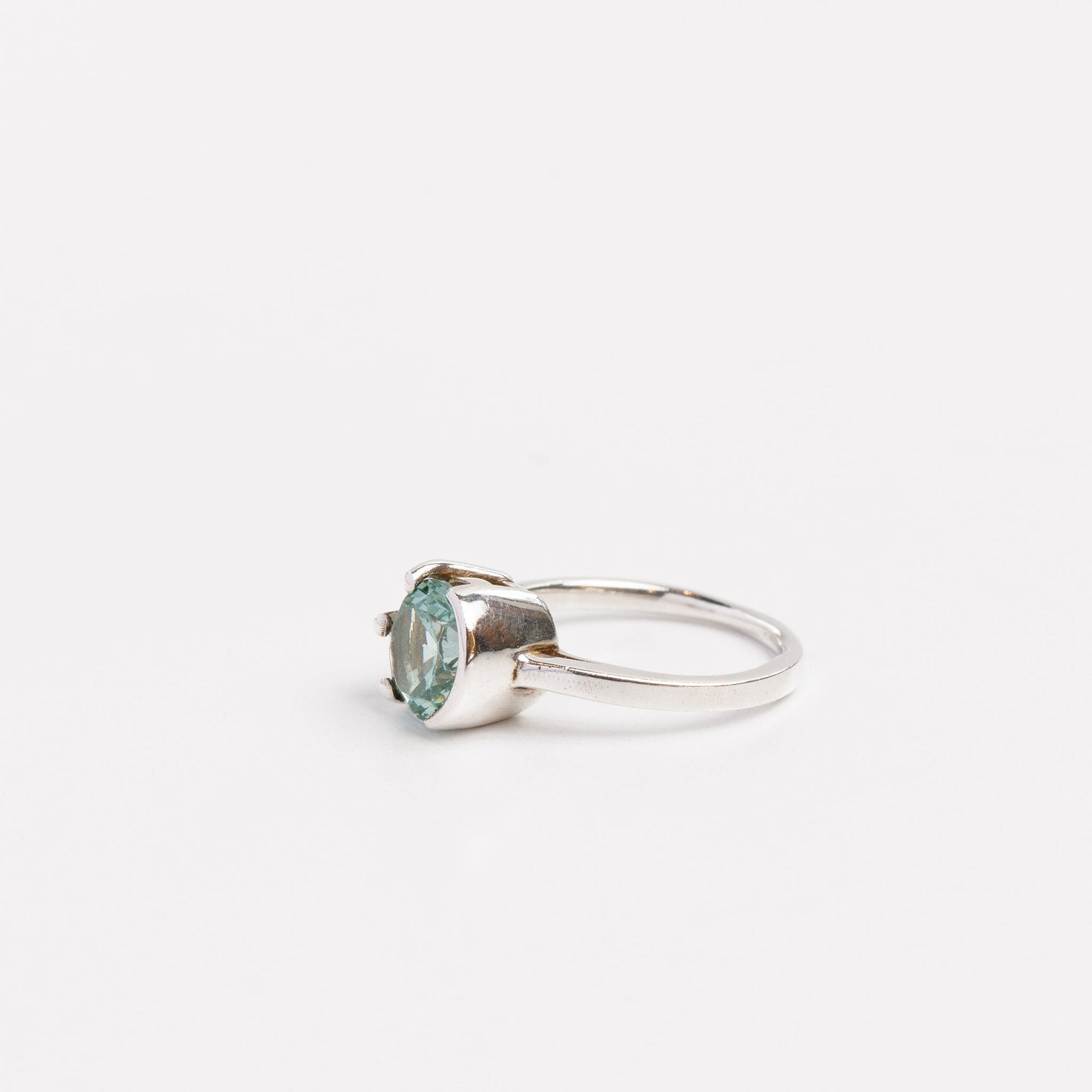 side view of the green moissanite half bezel ring on a white background