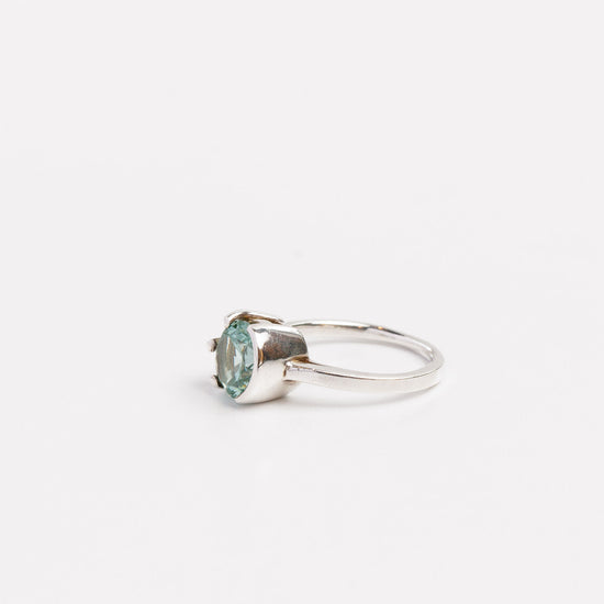 side view of the green moissanite half bezel ring on a white background