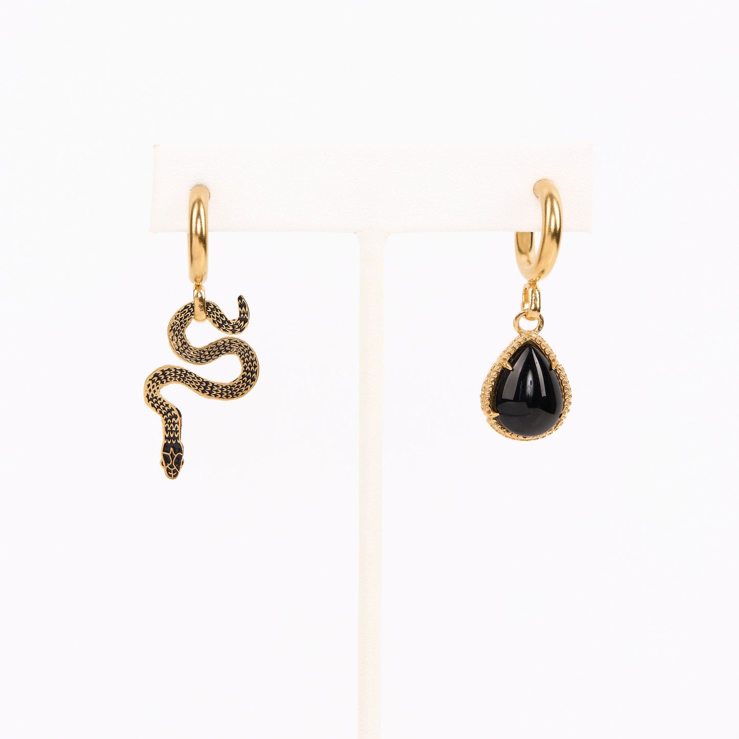 asymmetrical huggie earrings, one with a pear shaped onyx and one with a decorative snake