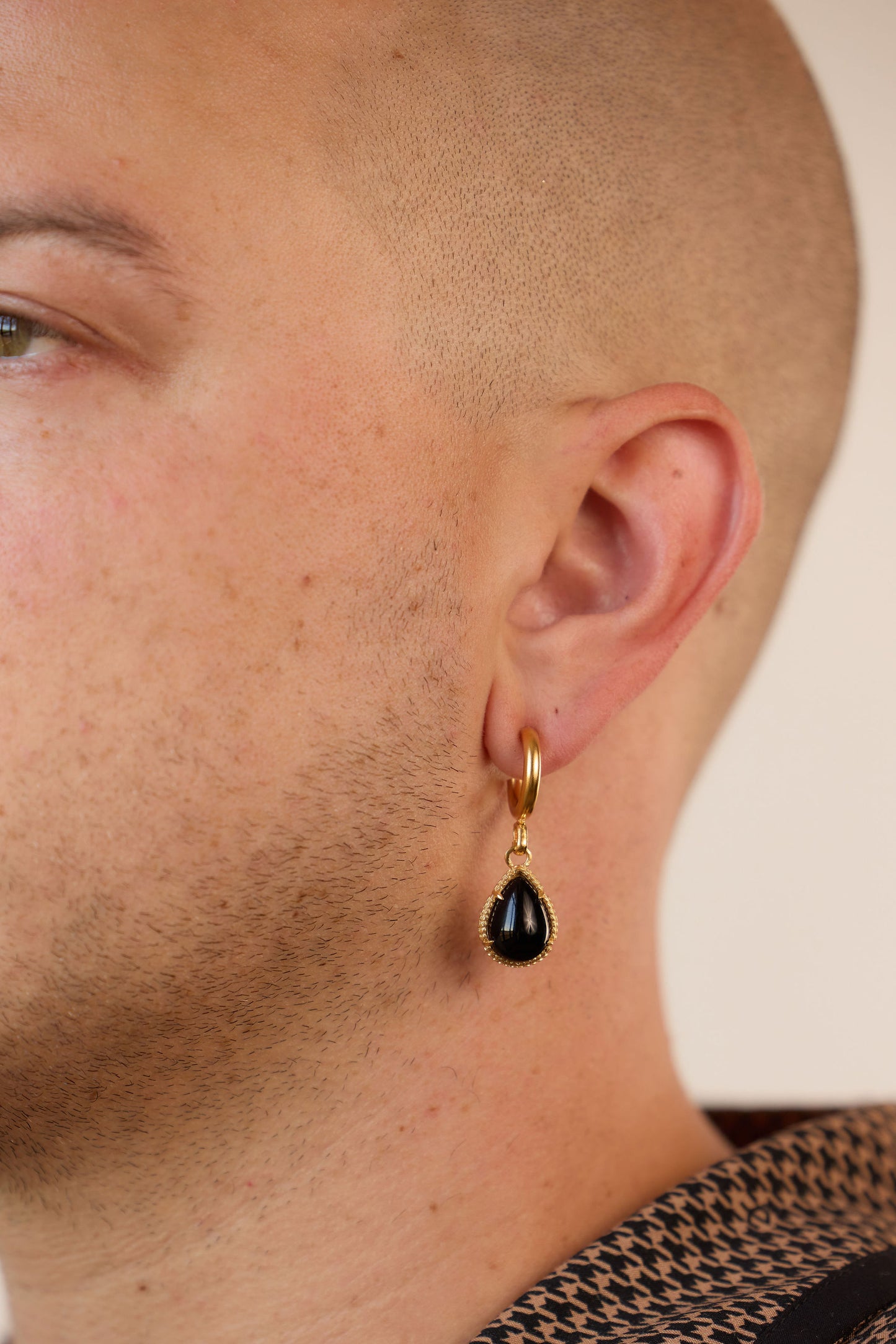 asymmetrical huggie earrings, one with a pear shaped onyx and one with a decorative snake on a model