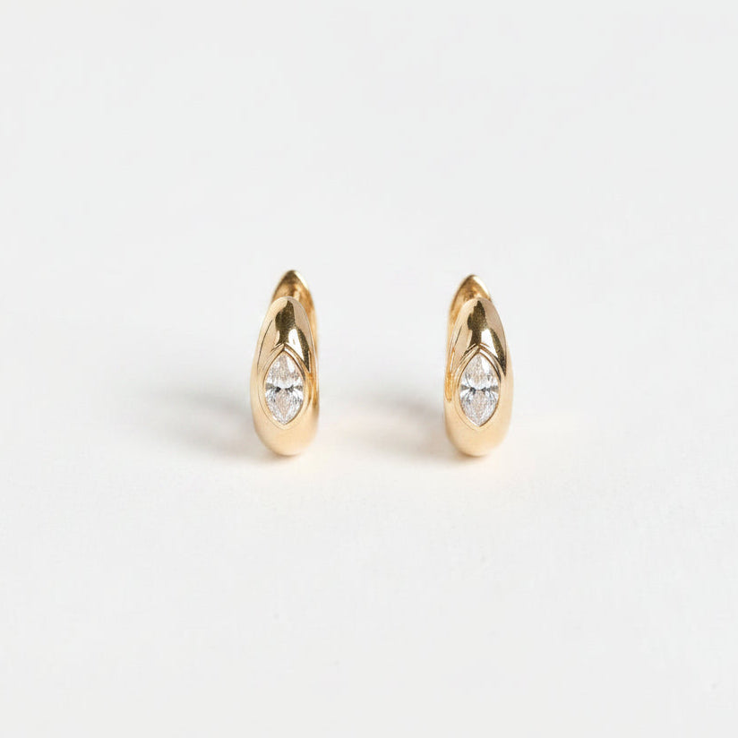 Gold hoop earrings with small stones on a light gray background