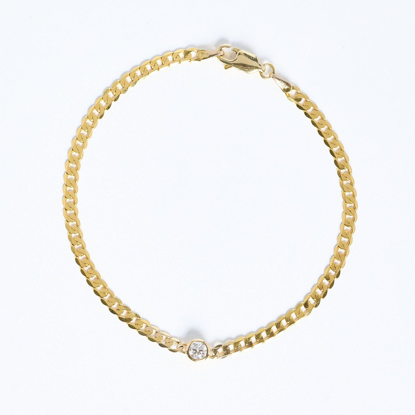 Gold chain bracelet with a small diamond on a white background