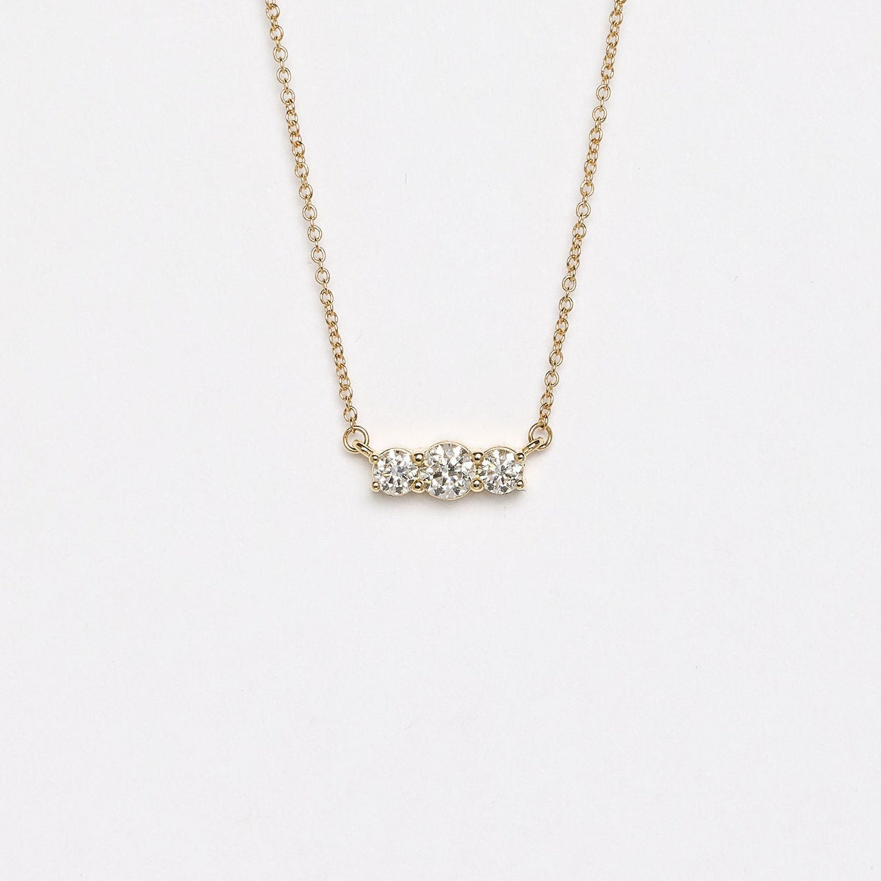 Gold necklace with small diamonds on a light gray background