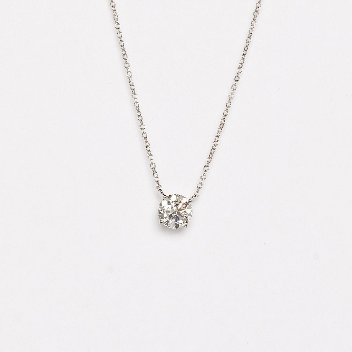 Silver necklace with a small round pendant on a white background