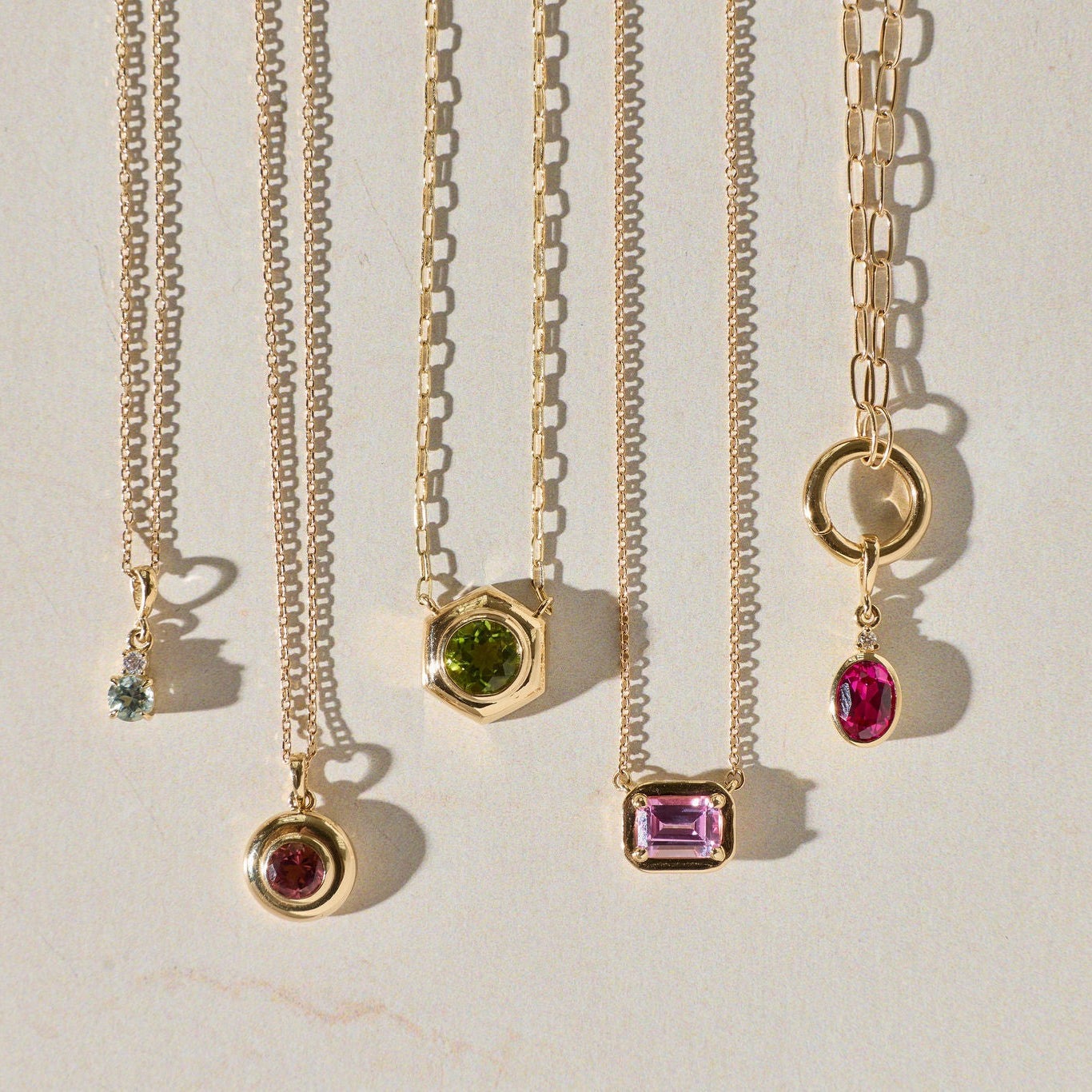 Set of gold necklaces with gemstone pendants on a light background