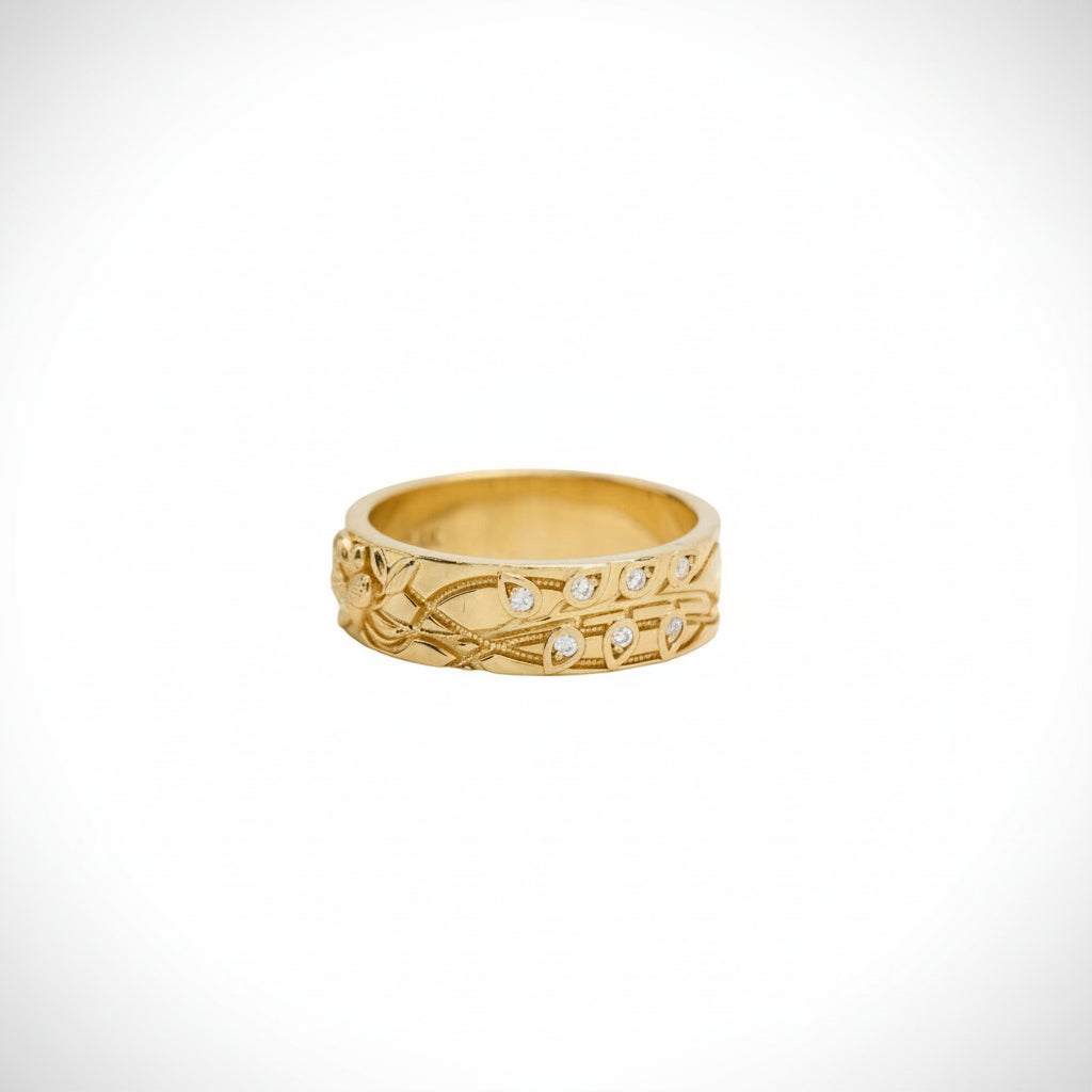 Gold ring with intricate design and small stones on a white background