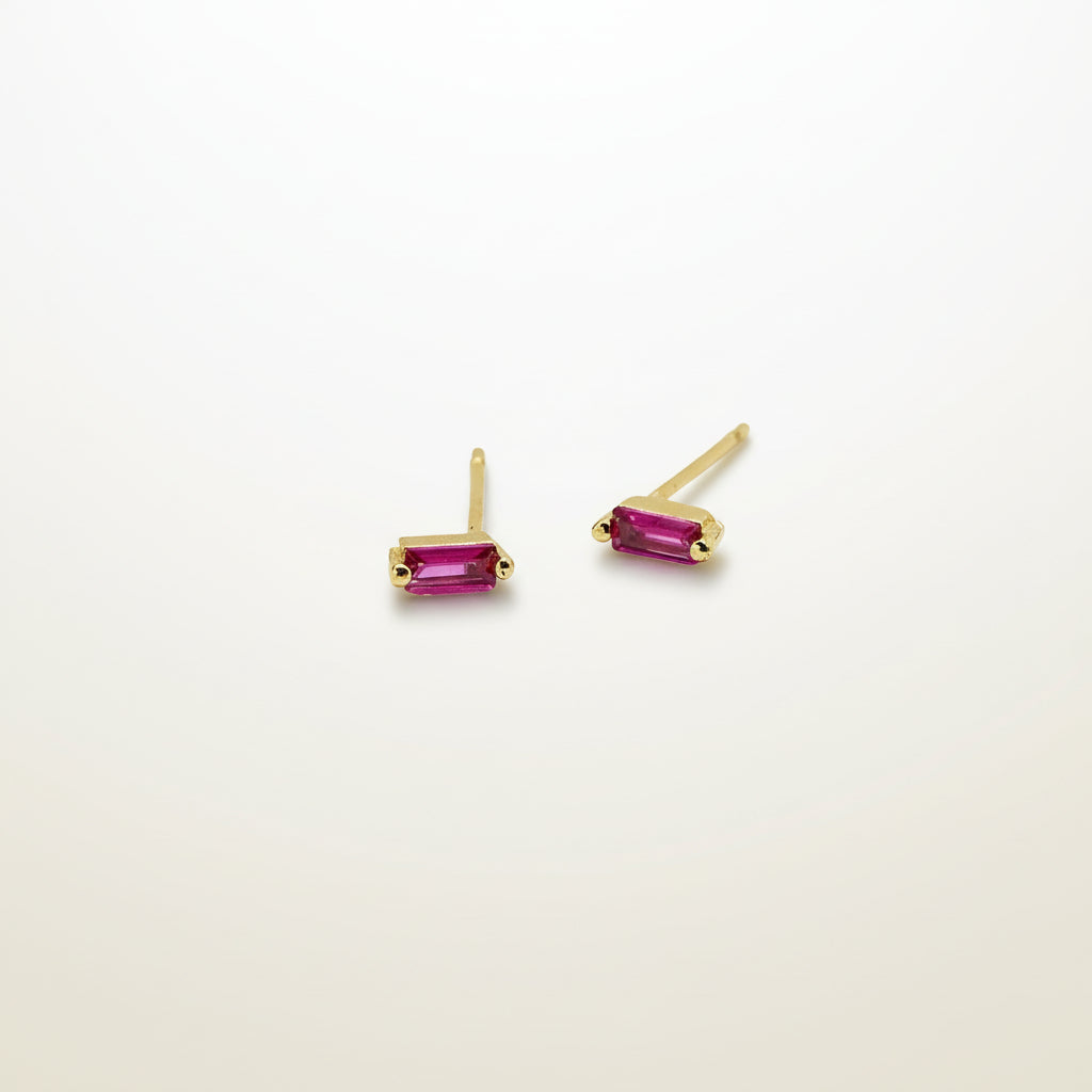 Gold earrings with pink gemstones on a white background