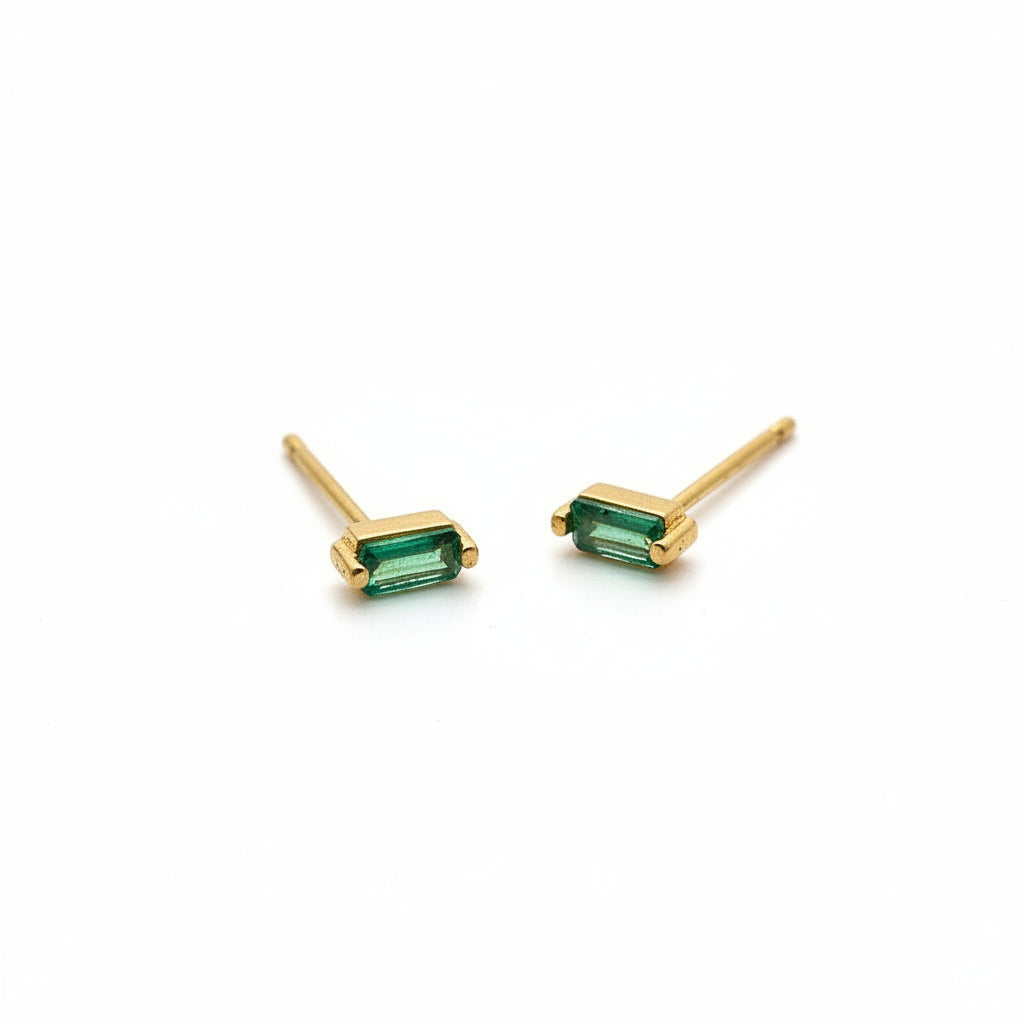 Gold earrings with green gemstones on a white background