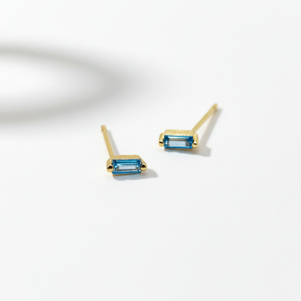 Gold earrings with blue gemstones on a white background