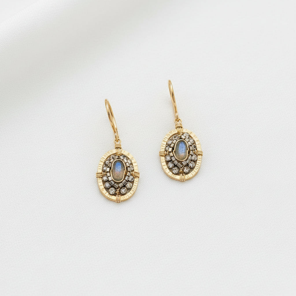 Gold earrings with gemstones on a light gray background