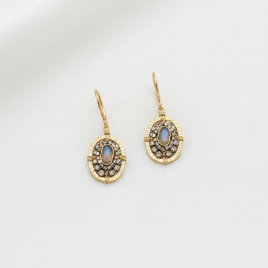 Gold earrings with gemstones on a light gray background