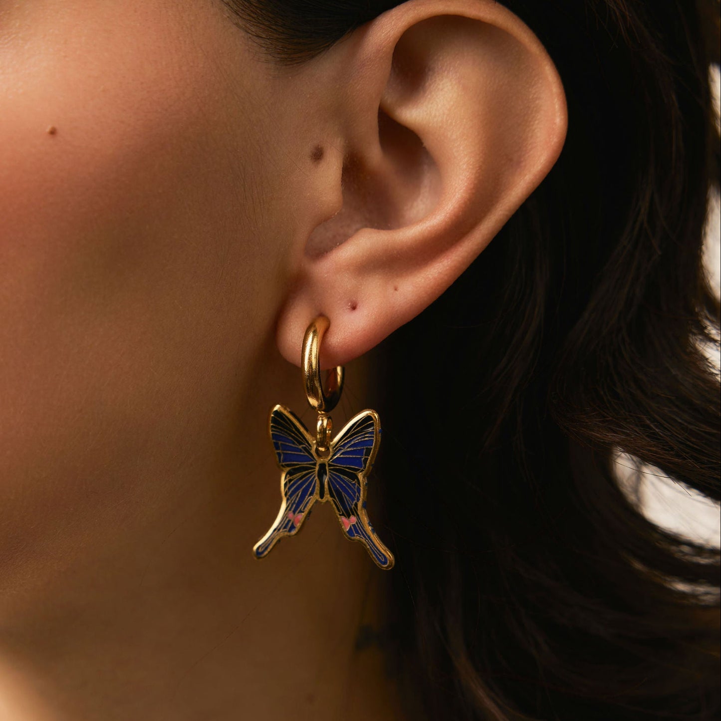 Close-up of a person wearing a butterfly earring.