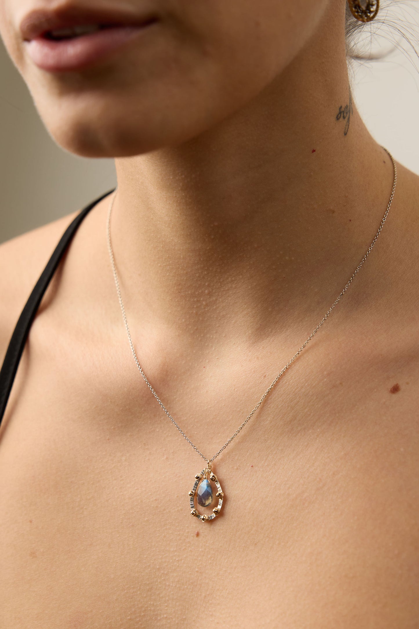 Necklace with a pendant worn by a person, focusing on the jewelry.