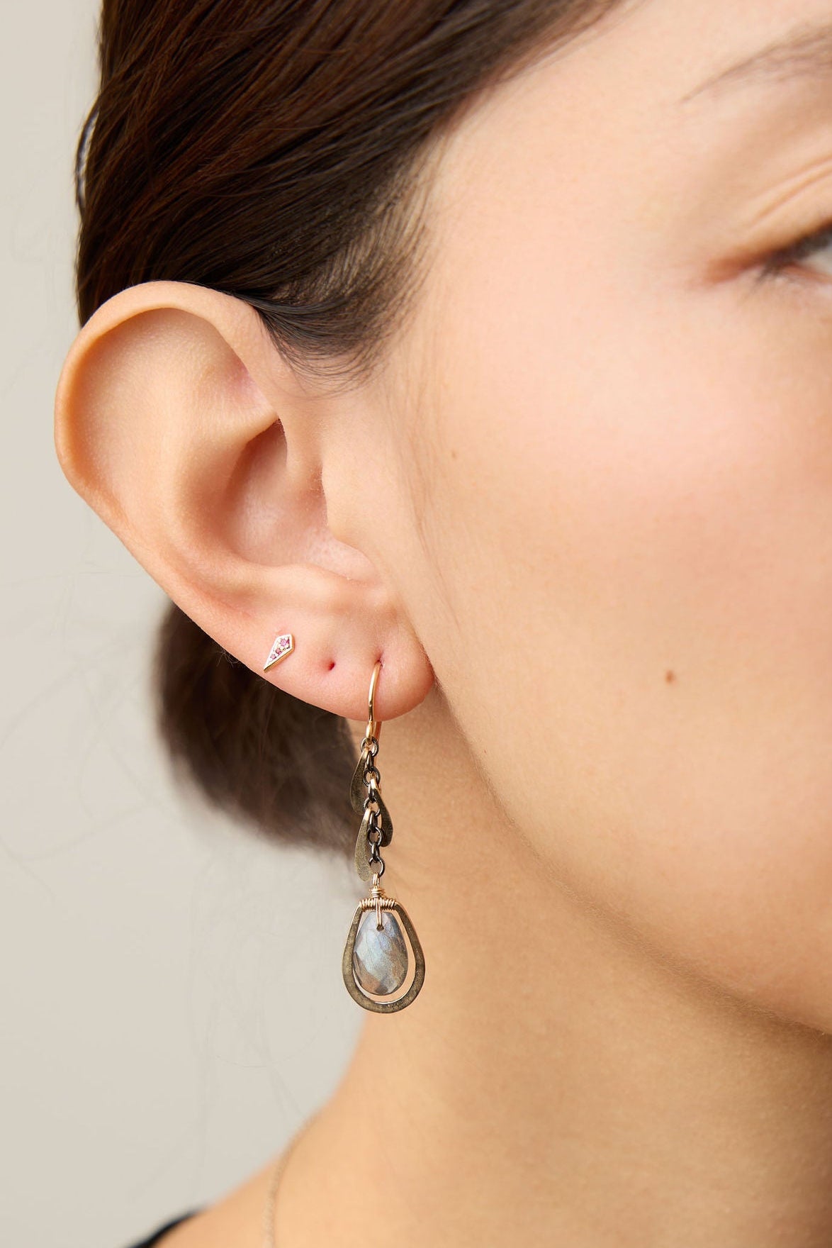 model wearing dangle gold and labradorite earrings with a neutral background
