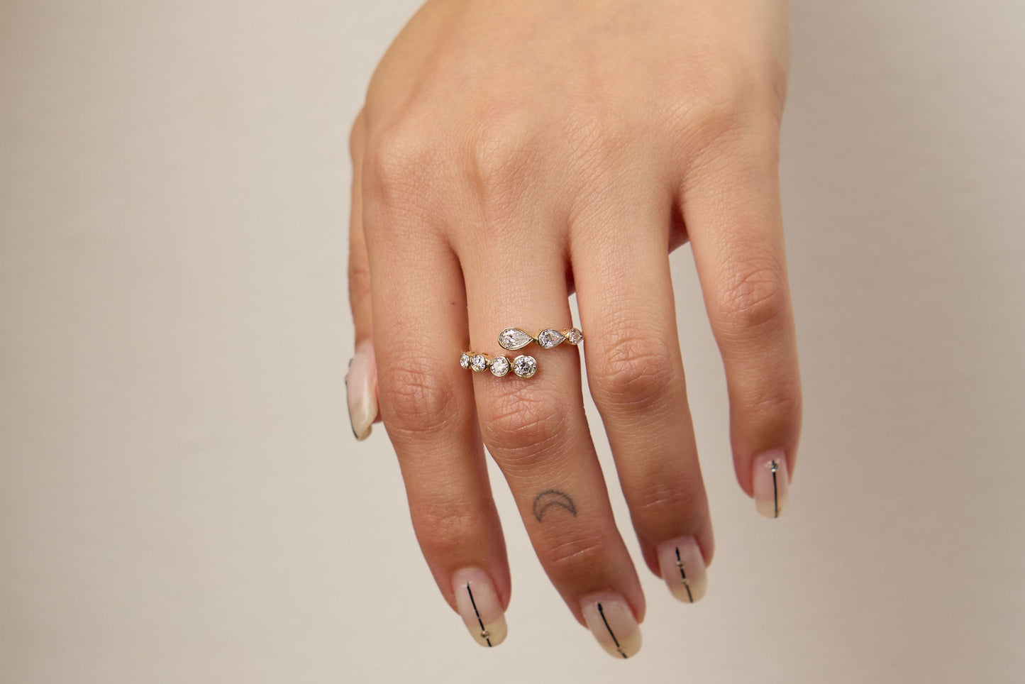 Hand wearing a ring with a beige background