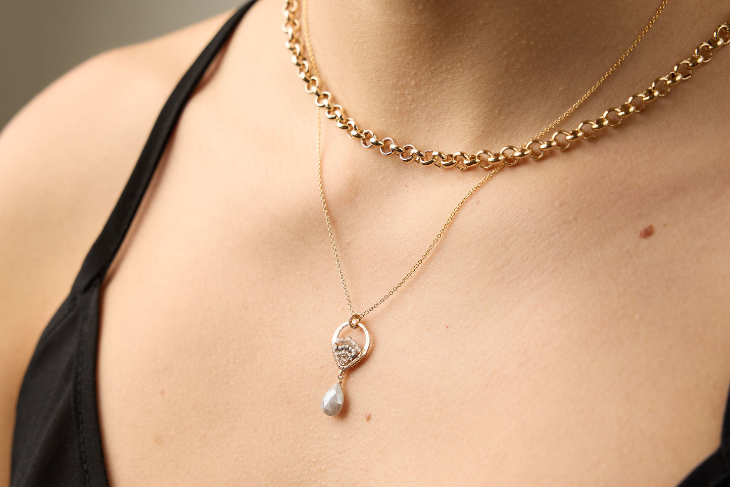 Close-up of a person wearing a gold chain necklace with a pendant.