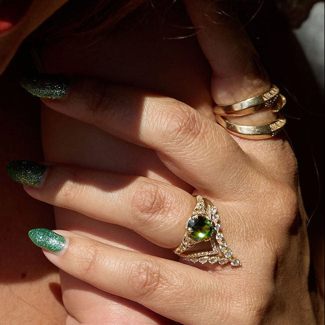 Close-up of a woman holding a baby's foot with visible jewelry and tattoos.