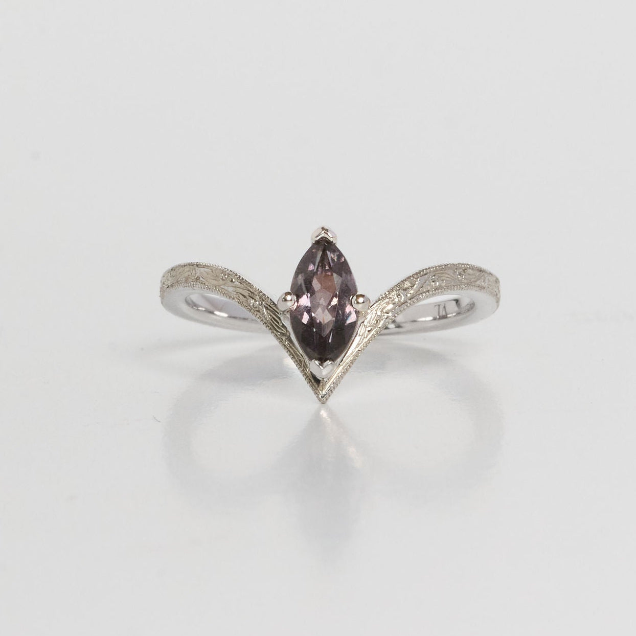 Silver ring with a marquise-shaped purple gemstone on a light gray background
