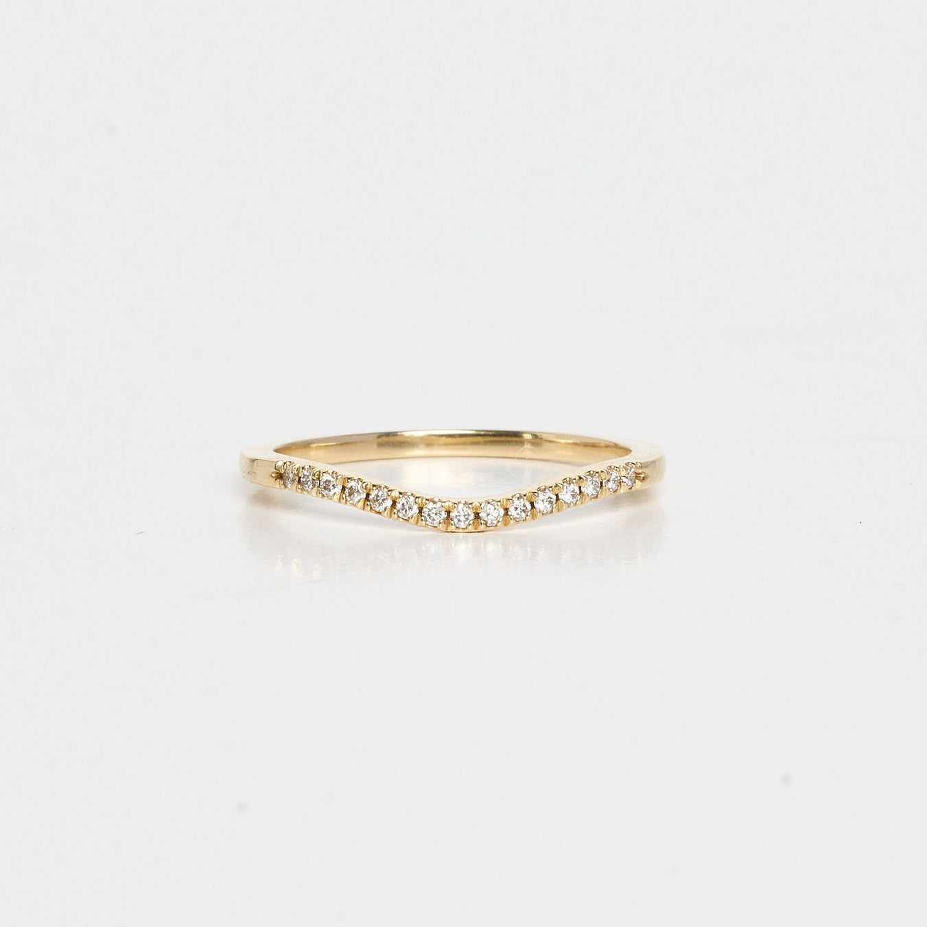 Gold ring with small diamonds on a light gray background