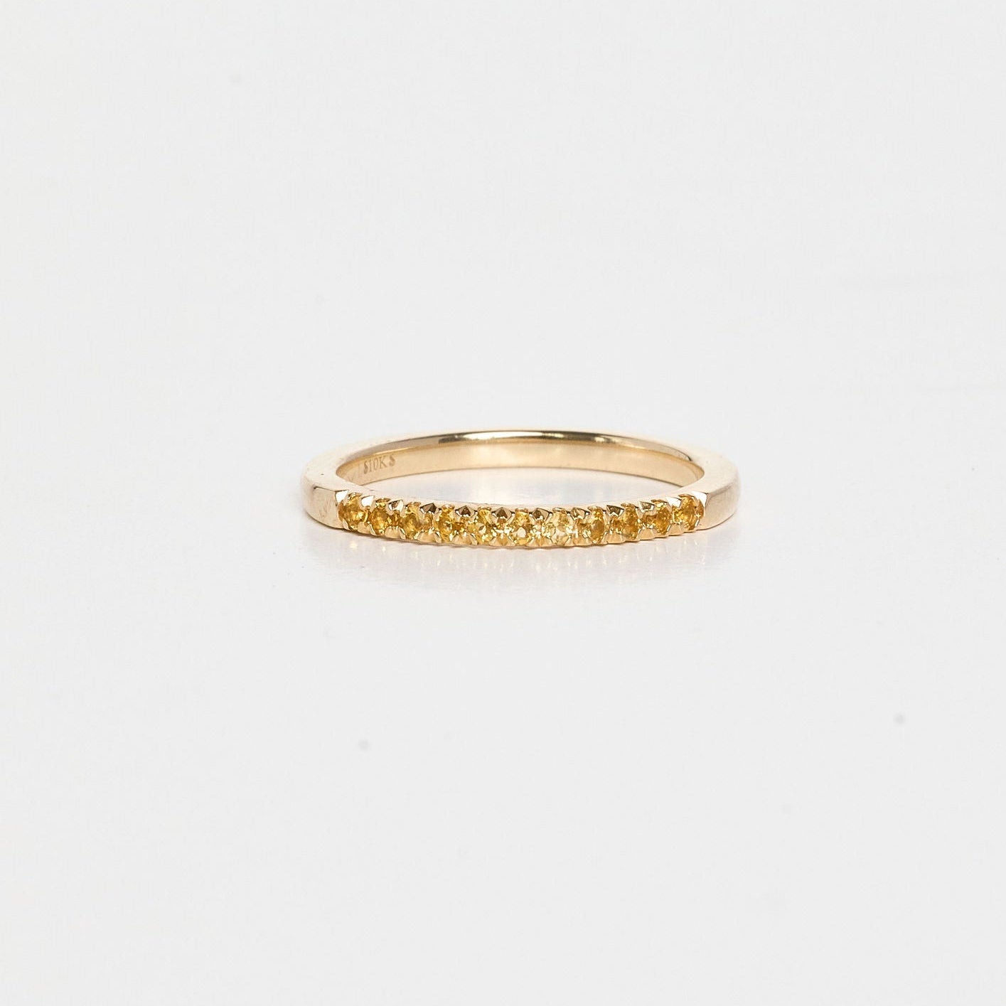 Gold ring with small stones on a light gray background