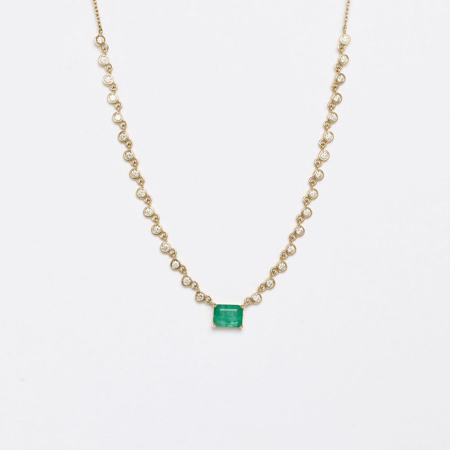 Necklace with an emerald pendant and white diamonds on a white background
