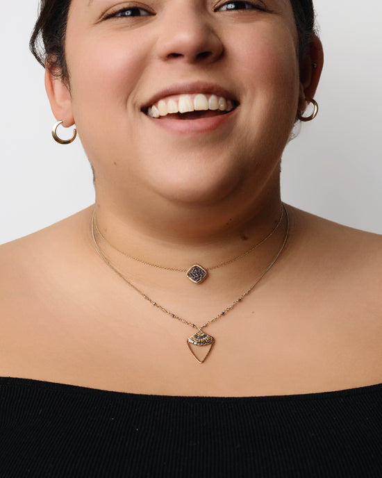 model wearing the teal beaded pendant layered with another necklace and gold hoops