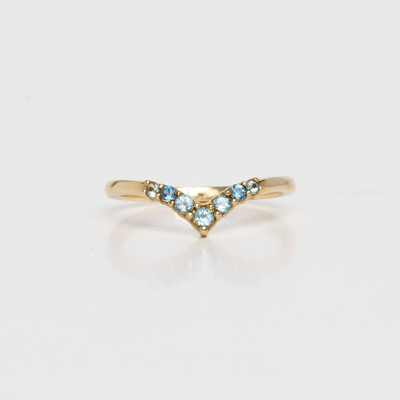 Gold ring with blue gemstones on a light gray background
