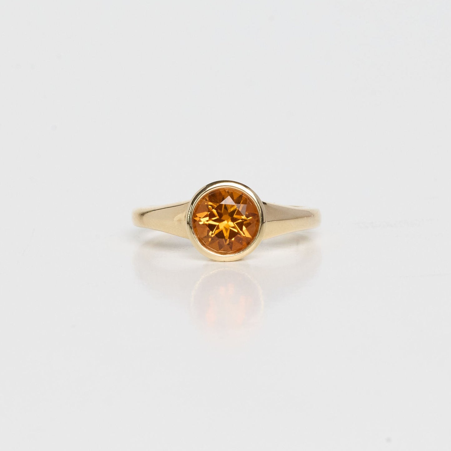 Gold ring with a round gemstone on a light gray background