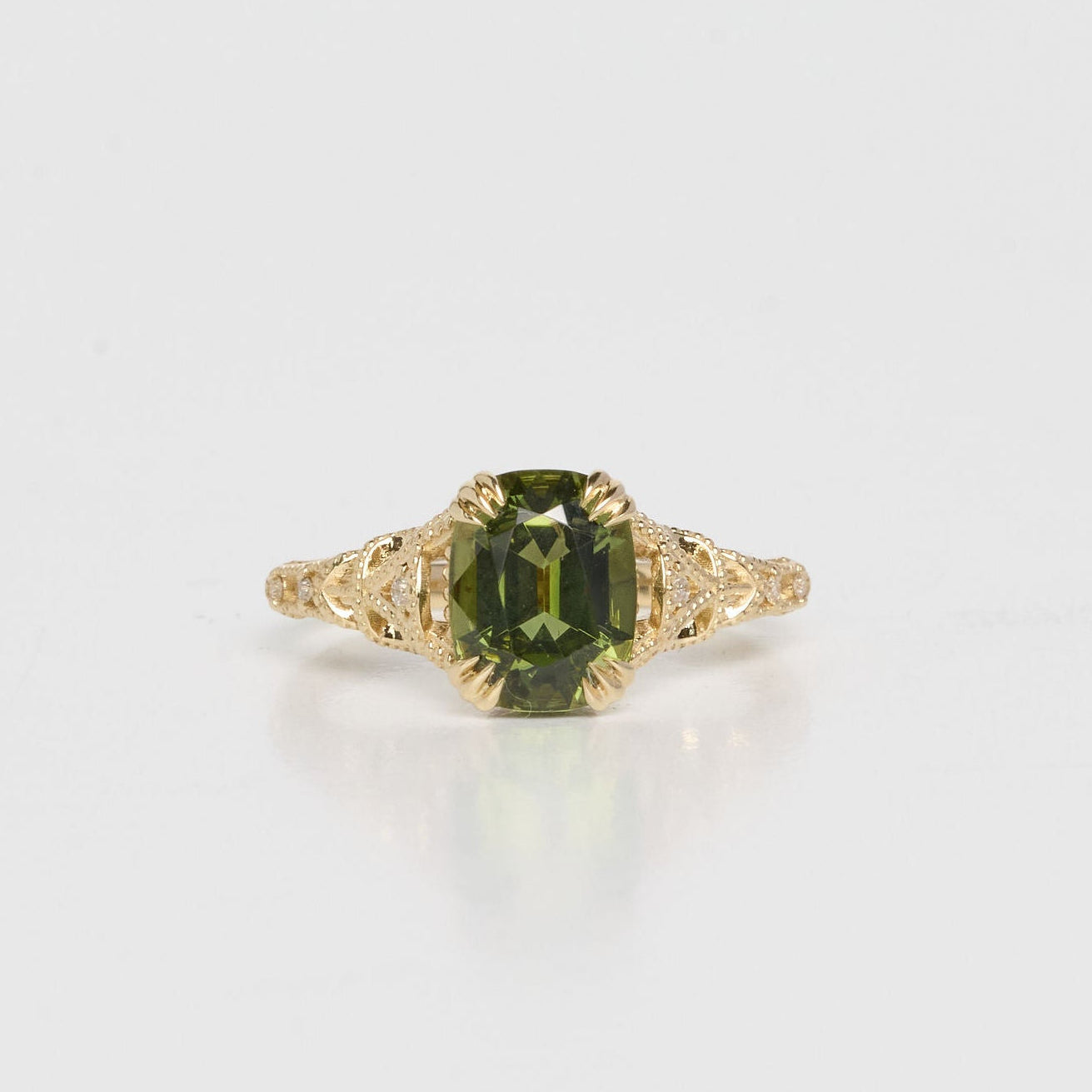 Gold ring with a green gemstone on a white background
