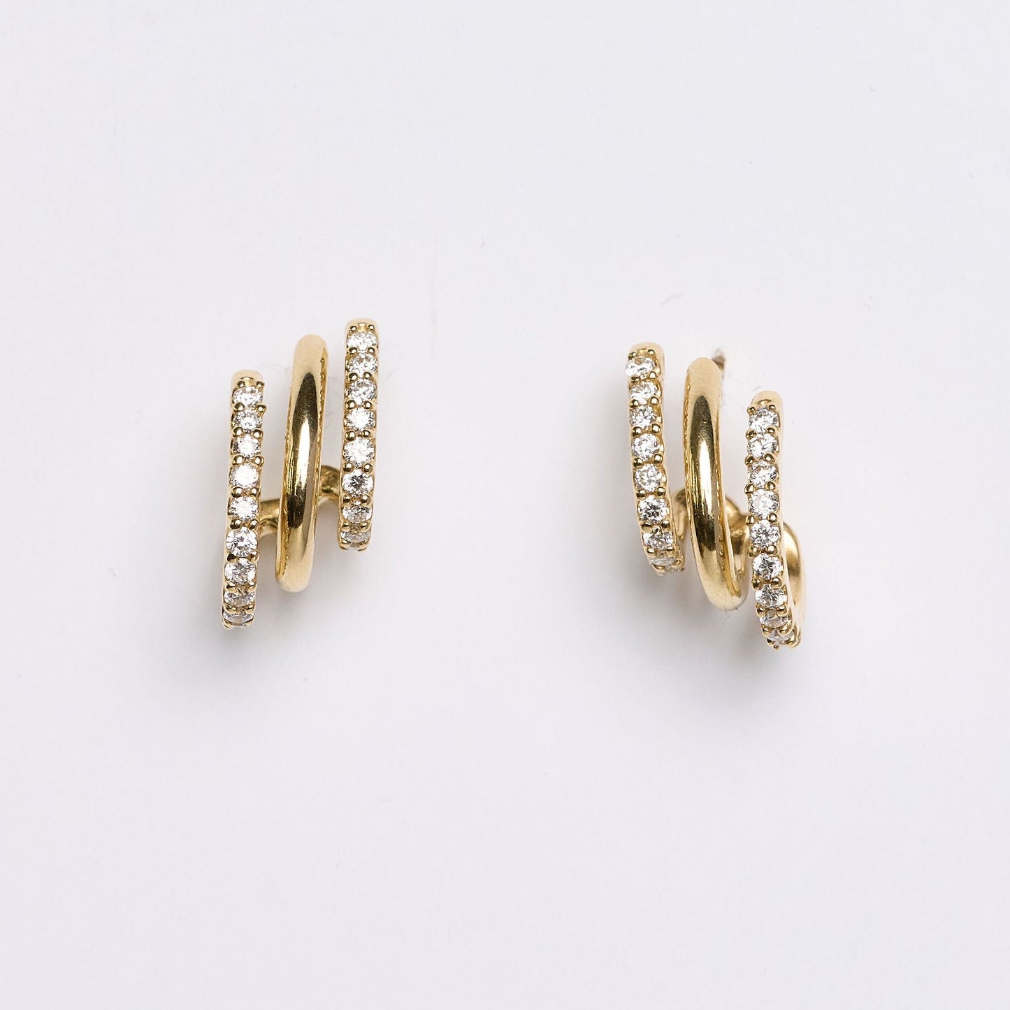 Gold hoop earrings with embedded stones on a light gray background