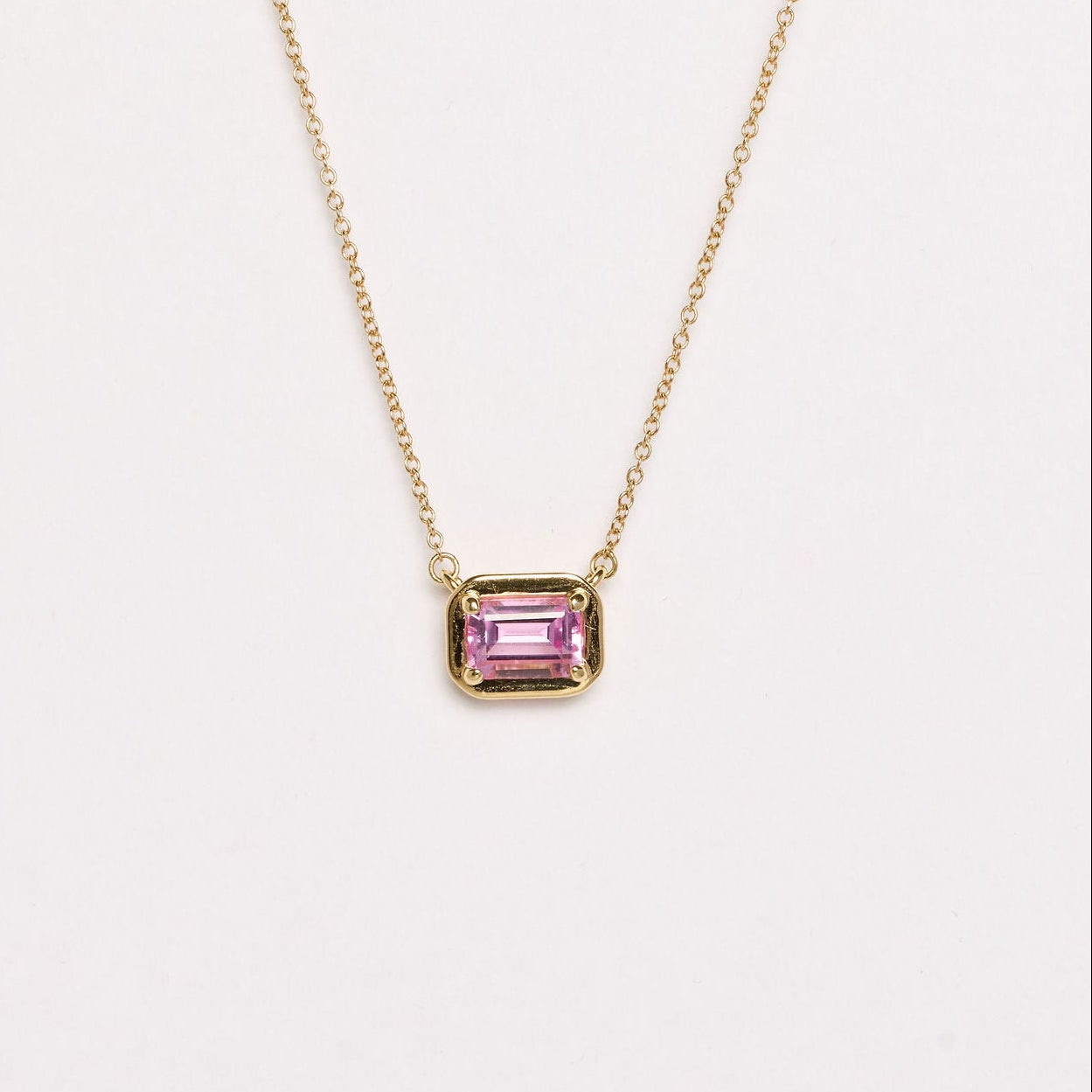 Necklace with a pink gemstone pendant on a light gray background