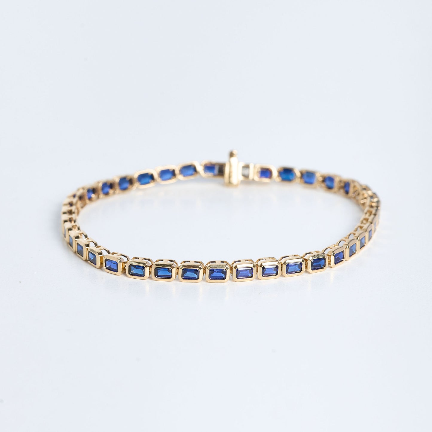 Gold bracelet with blue stones on a light gray background
