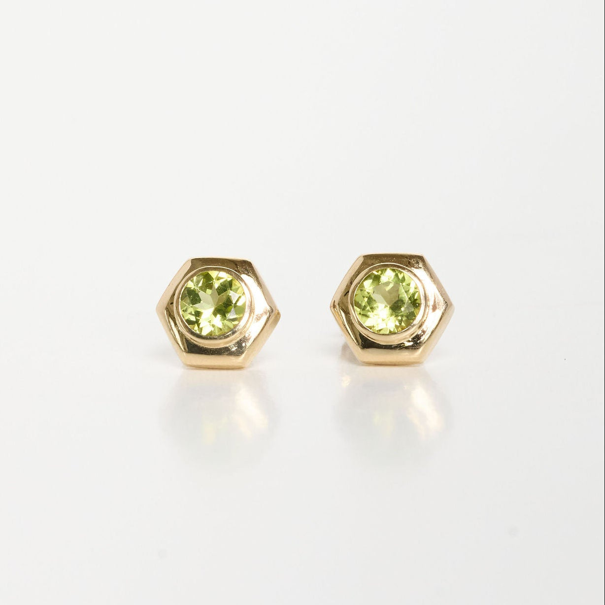 Gold earrings with green gemstones on a white background