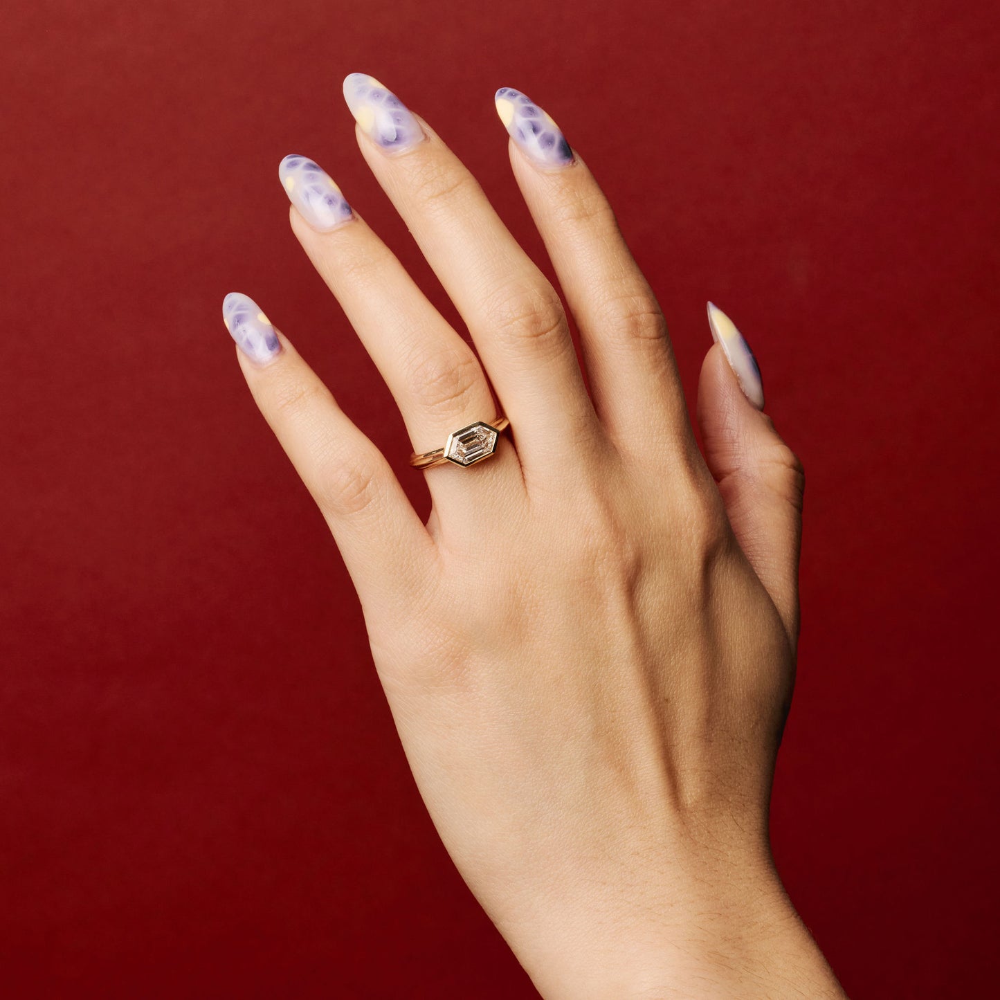 clsoe up of a hand wearing the element 3 ring on ring finger with red background