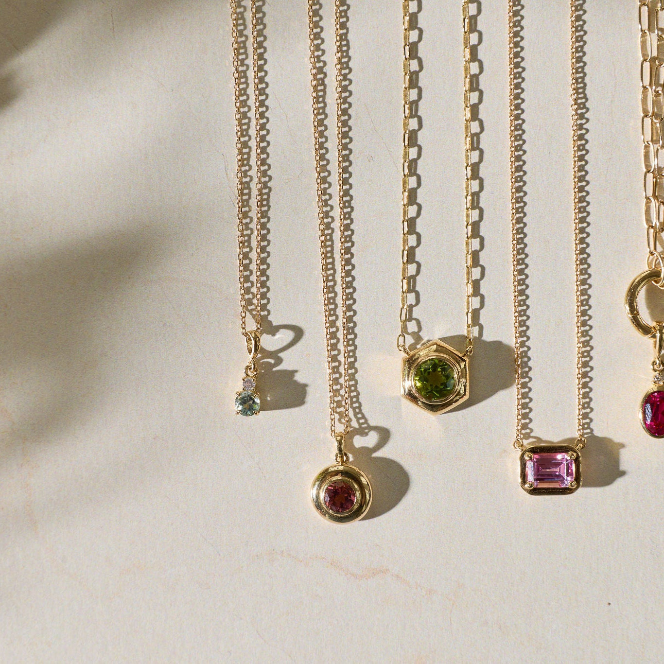 Gold necklaces with gemstone pendants on a light background
