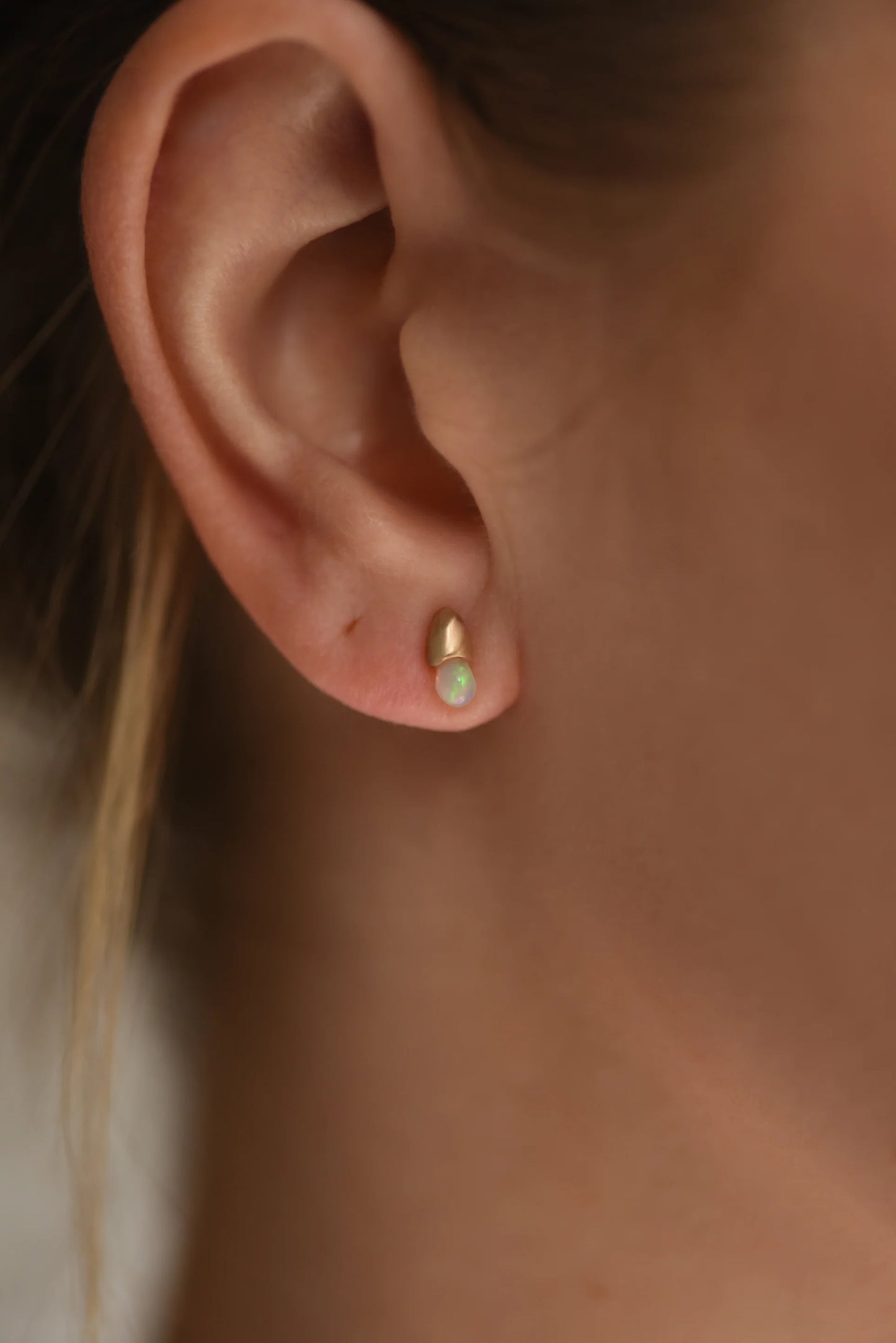 close up of a model wearing the opal droplet stud earrings