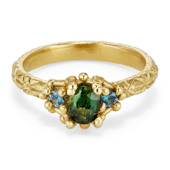 yellow gold engraved with with oval green sapphire and two round blue sapphires on white background