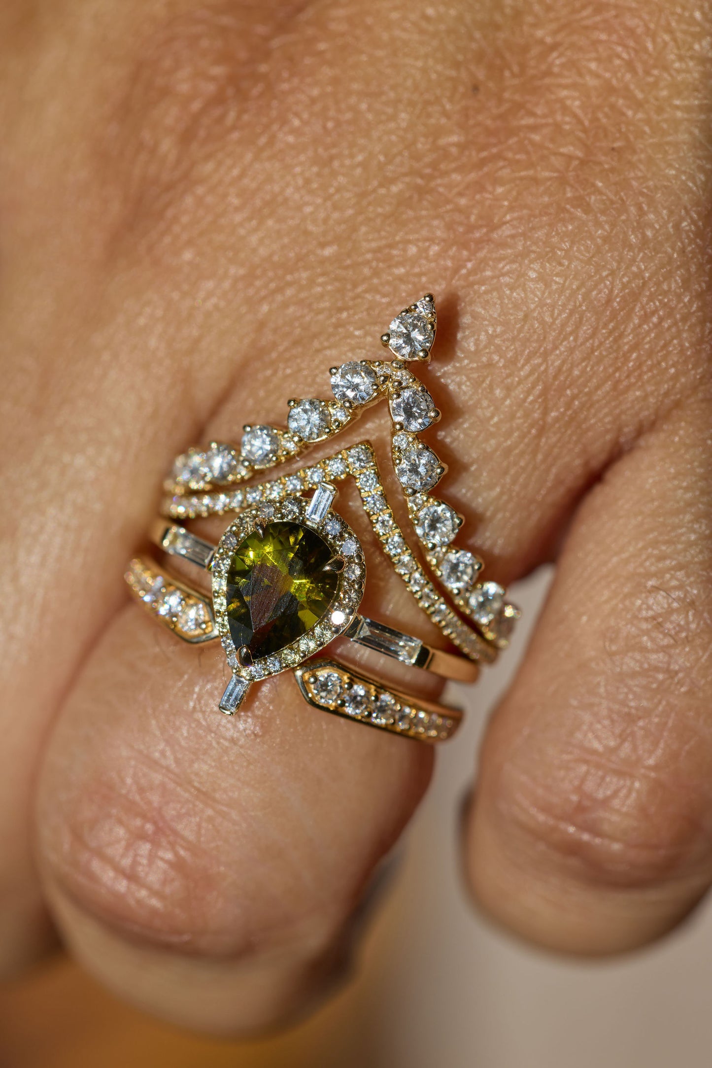 Gold ring with green gemstone and diamonds on a finger