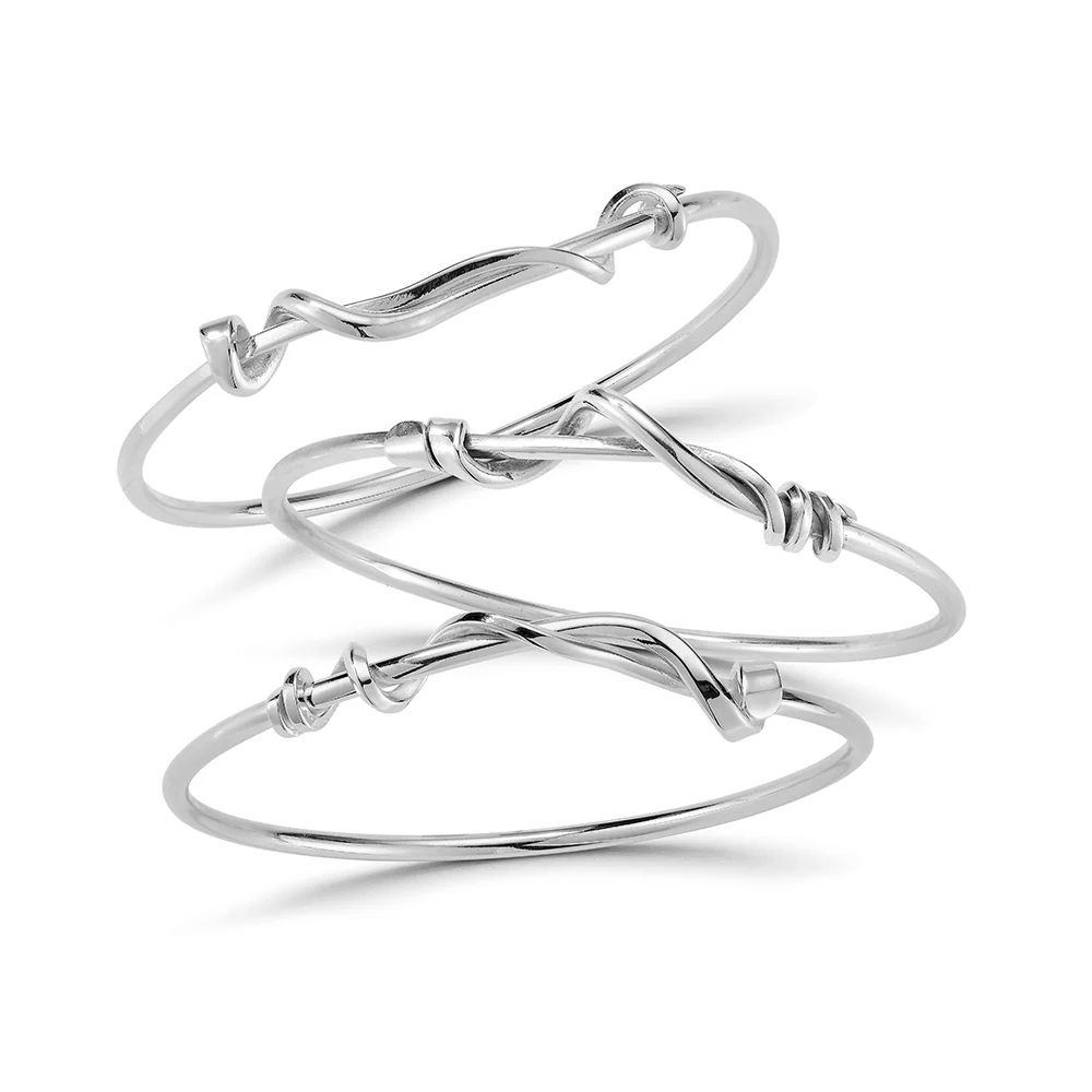 three twisted silver bangles on a white background