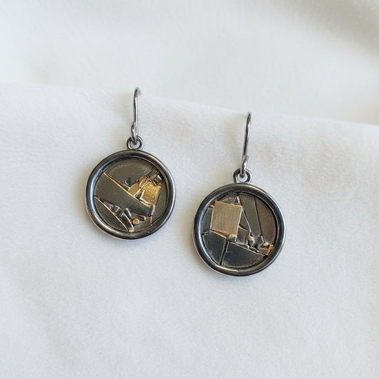 Pair of earrings with circular designs on a black background