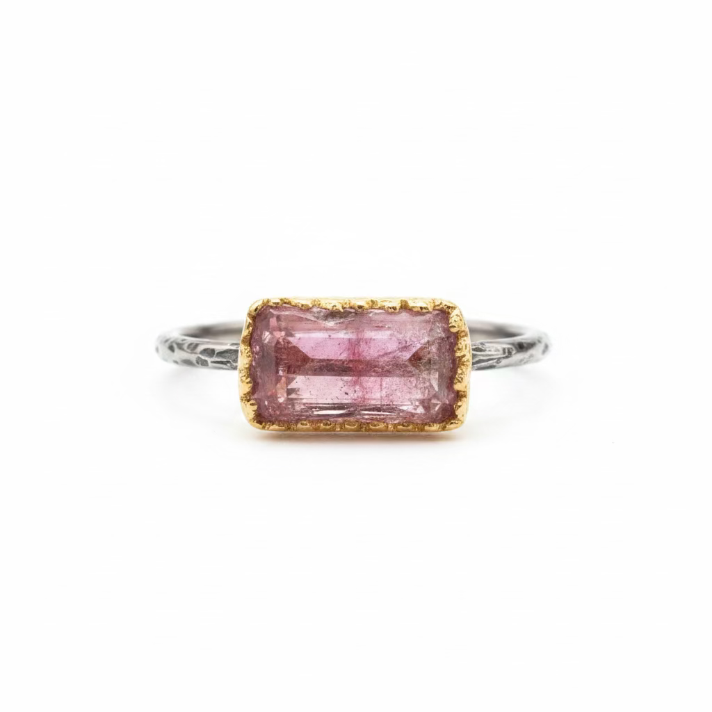 Ring with a rectangular gemstone, scalloped gold bezel, and black silver band. 