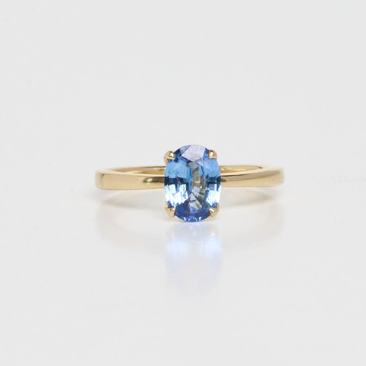 Gold ring with a blue gemstone on a light gray background