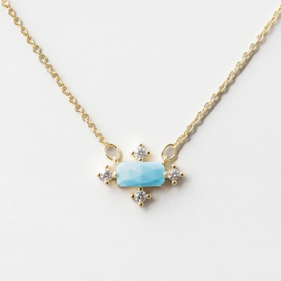 Load image into Gallery viewer, A necklace on a gold chain that has a central turquoise baquette surrounded by Cubic Zirconia on the north, south, east and west points.
