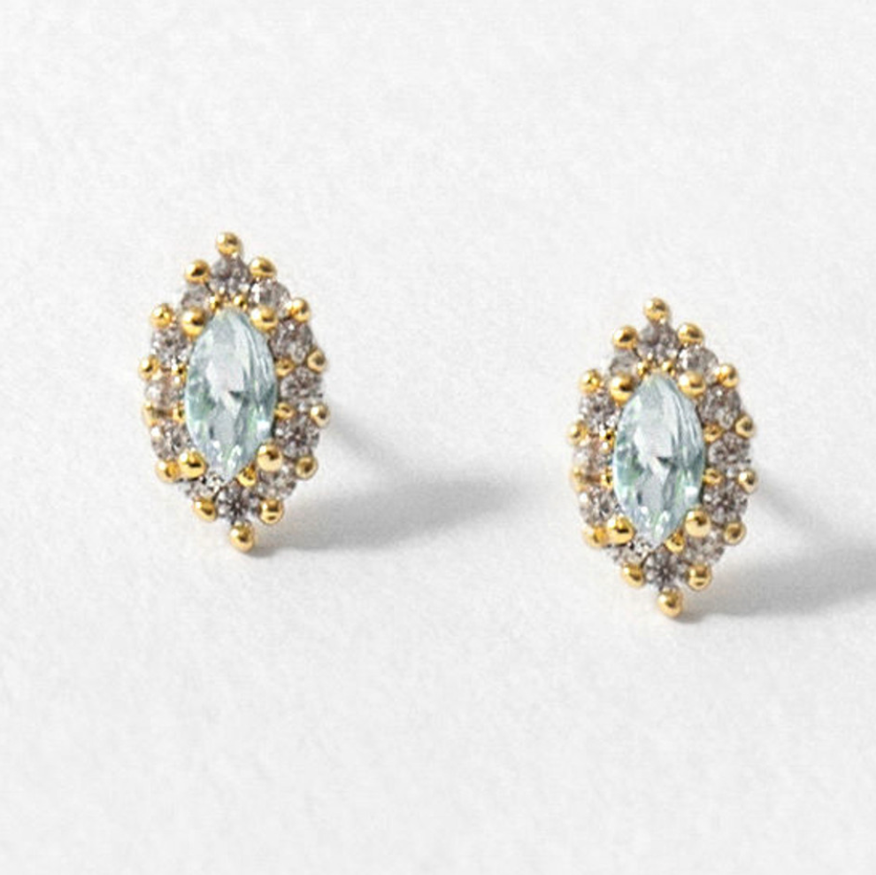 stud earrings on white background with marquise shaped blue topaz gemstones with a cubic zirconia halo and gold accents