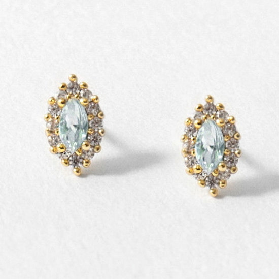 Load image into Gallery viewer, stud earrings on white background with marquise shaped blue topaz gemstones with a cubic zirconia halo and gold accents
